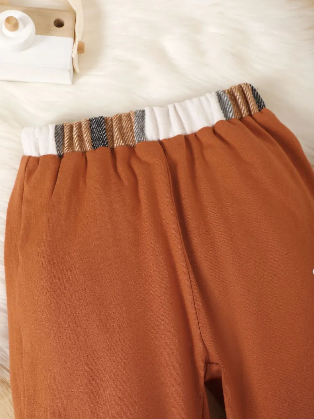children's two-piece outfit with a button up color block top and matching pants displayed on flat neutral lighting
